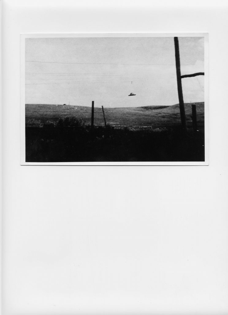 Black and white photograph of a fake UFO hanging from a wire