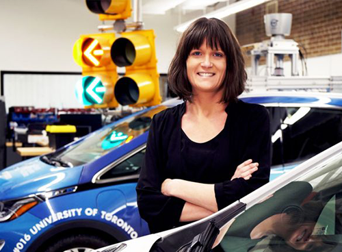Angela Schoellig proudly standing in front of the auToronto vehicle in the autonomous robotics lab